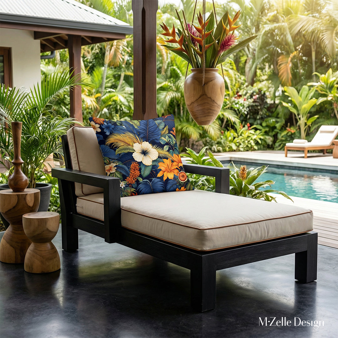 Photographie professionnelle gros plan sur une chaise longue en bois noir structure épaisse et assises écrues moderne finitions marron, orné d'un grand coussin colibri, exposé sur la véranda avec vue sur jardin tropical, et bord de piscine , inspiration architecture créole modernisée.