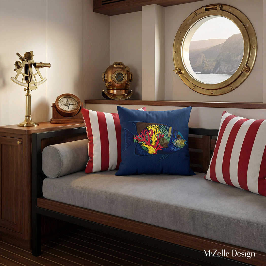 Photographie d'intérieur de style éditorial, intérieur d'une cabine de yacht au design raffiné et minimaliste. Gros plan sur la vue de face d'un lit de repos minimaliste avec un grand coussin au centre, entouré de deux coussins rayés rouges et blancs. Le mobilier est épuré et élégant