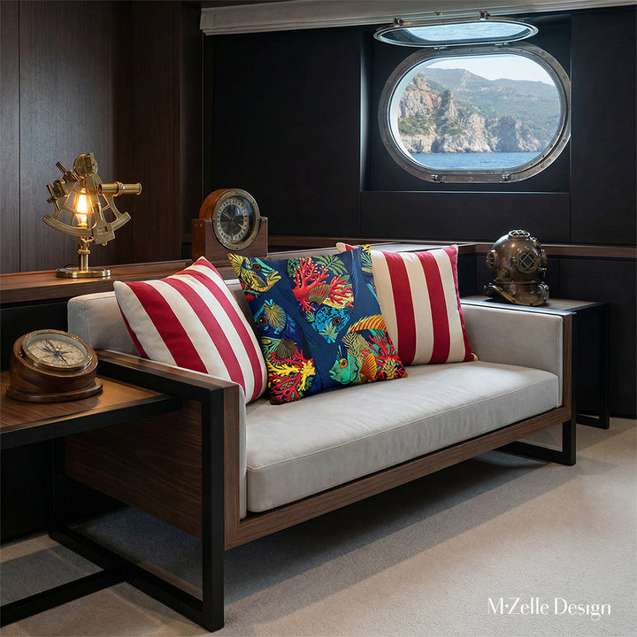Photographie d'intérieur de style éditorial, intérieur d'une cabine de yacht au design raffiné et minimaliste. Gros plan sur la vue de face d'un lit de repos minimaliste avec un grand coussin au centre, entouré de deux coussins rayés rouges et blancs. Le mobilier est épuré et élégant.