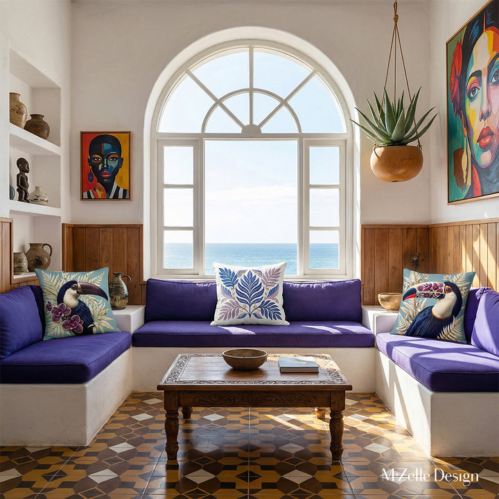 Photo professionnelle hautement détaillée, salon Arty dans une villa cubaine baignée de soleil avec murs blanchis à la chaux, fenêtre en demi-lune vue mer et canapé intégré dans le mur en dessous, assises violet foncé avec un coussin motif toucan de chaque côté.