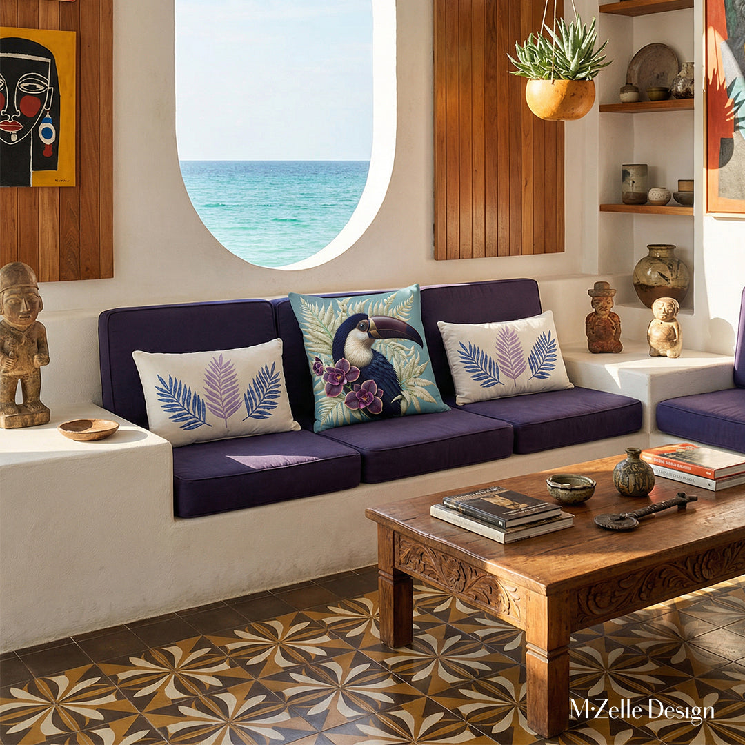 Photo professionnelle villa cubaine baignée de soleil avec murs blanchis à la chaux, découpe murale en demi-lune vue mer et canapé intégré dans le mur en dessous, assises violet foncé avec un large coussin motif toucan, et autour 2 coussins rectangulaires.