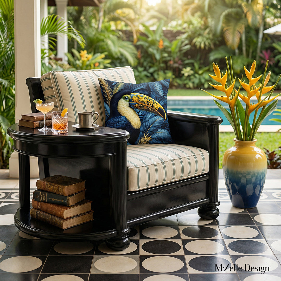 Photographie professionnelle extrêmement détaillée, esprit estival, vue de face en gros plan sur 1 fauteuil en bois peint noir laqué, structure épaisse table basse arrondie intégrée sur le côté, assises écrues, orné de grands coussins motif toucans, exposé sur la véranda , vue sur jardin luxuriant et piscine.