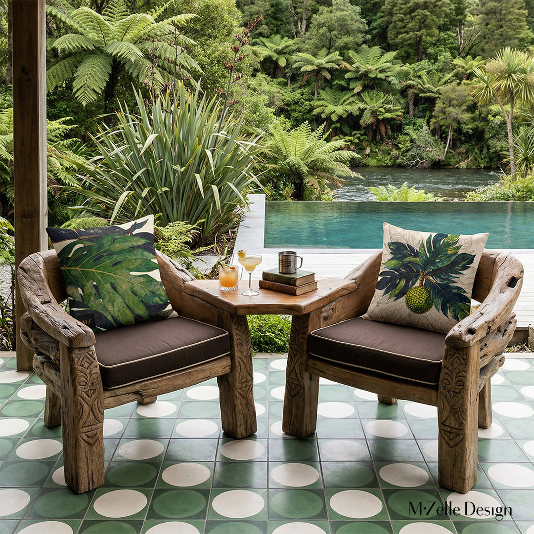 Photographie professionnelle extrêmement détaillée d'une terrasse d'écolodge esprit nature, vue de face en gros plan sur 1 fauteuil orné d'un grand coussin motif feuilles et fruit à pain mzelle design,  jardin botanique, livres et cafetière ancienne et tasse en étain sur la table basse, une piscine extérieure à débordement en bord de rivière, ambiance cosy et invitante.