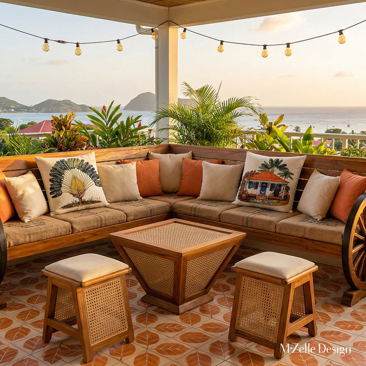 Photo professionnelle lifestyle d'une terrasse aux Antilles, vue sur piscine à débordement et montagne, vue de face d'un banc d'angle en forme de L, avec 2 roues de charrettes en teck vernis aux extrémités, assises en toiles de jute noir , 2 larges coussins motifs case créole et arbre du voyageur, une table basse en forme de pyramide inversée en bois et finitions en cannage, 2 tabourets en bois et cannage assortis assises écrues.