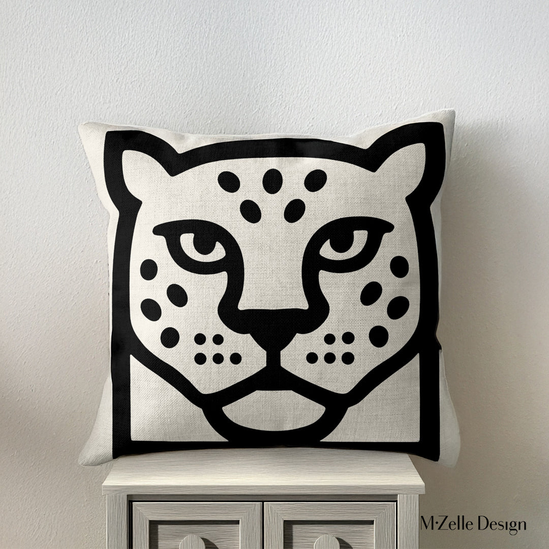 coussin graphique Mzelle Design posée sur un meuble - tête de jaguar bicolore noir et écru, brut et élégant, entre art tribal et design contemporain