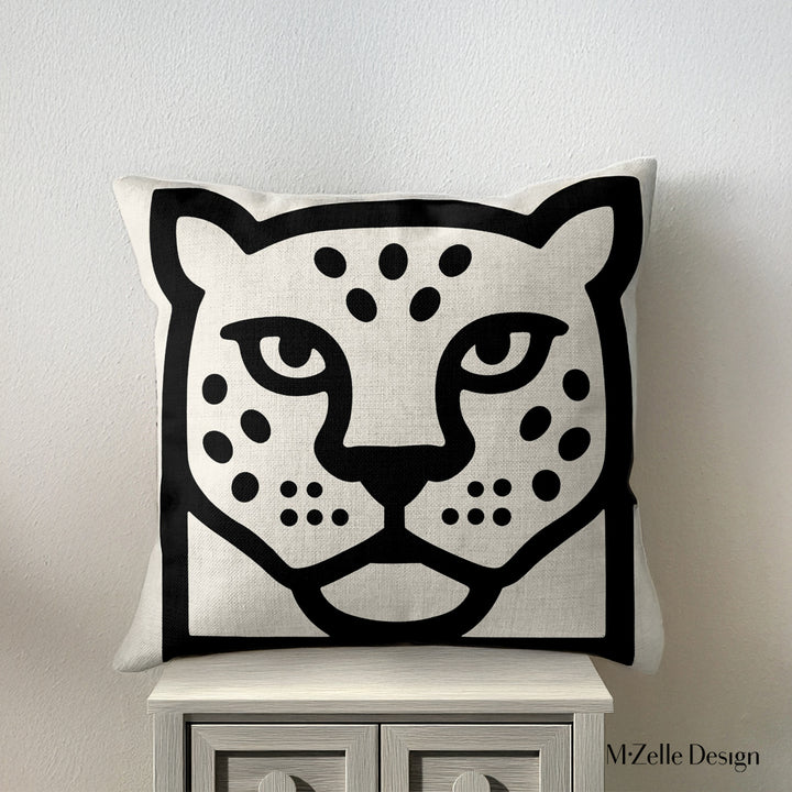coussin graphique Mzelle Design posée sur un meuble - tête de jaguar bicolore noir et écru, brut et élégant, entre art tribal et design contemporain