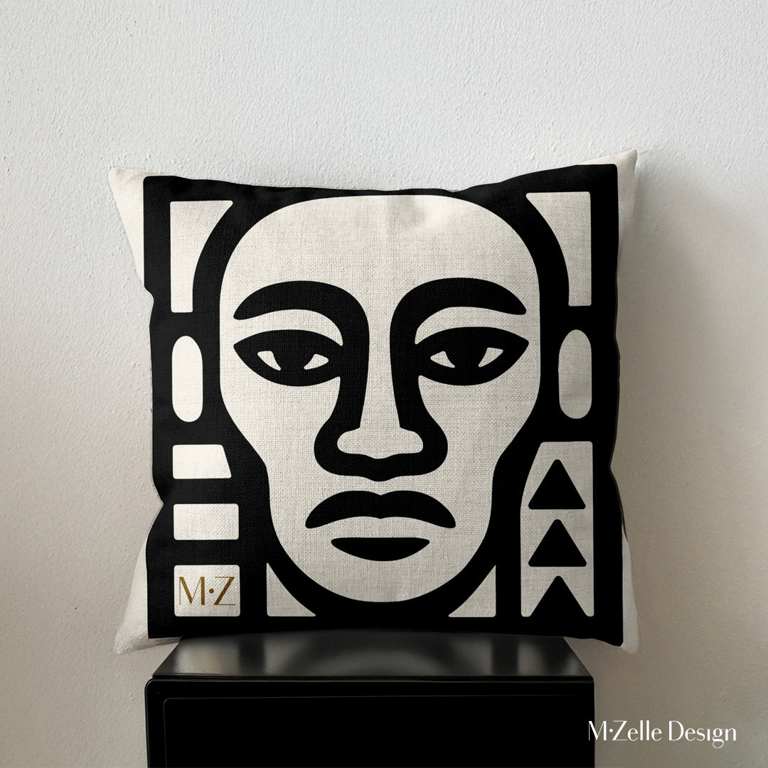 coussin graphique Mzelle Design posé sur un meuble noir - tête de guerrier bicolore noir et écru, brut et élégant, entre art tribal et design contemporain