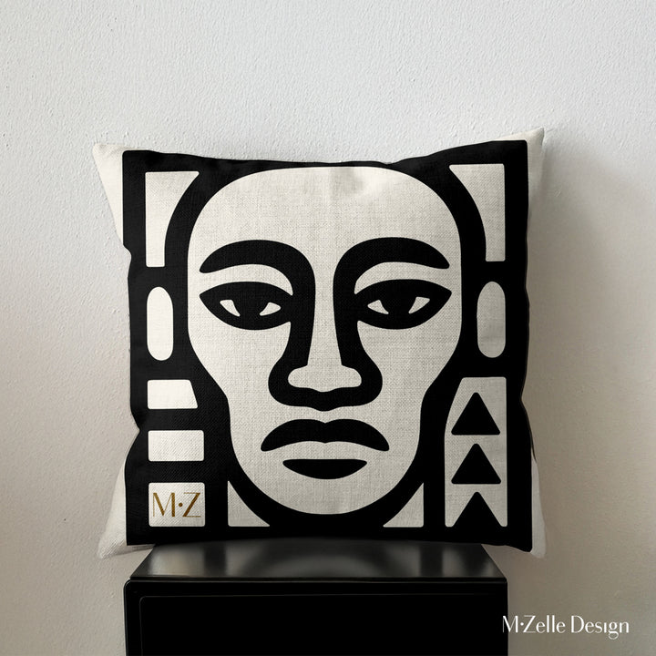 coussin graphique Mzelle Design posé sur un meuble noir - tête de guerrier bicolore noir et écru, brut et élégant, entre art tribal et design contemporain