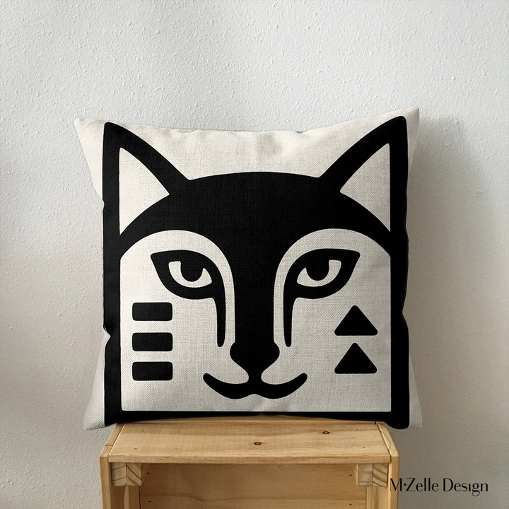 coussin graphique Mzelle Design posé sur une caisse en bois - tête de renard bicolore noir et écru, brut et élégant, entre art tribal et design contemporain