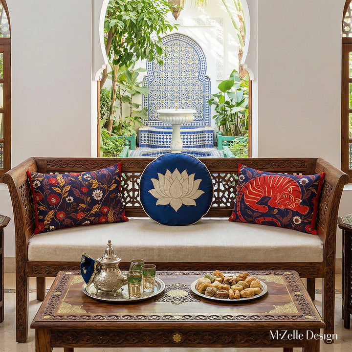 Photographie professionnelle extrêmement détaillée , Villa Riad lumineuse, vue de face d'un superbe banc, assises de tissu écru orné de 2 coussins rectangles motifs indiens mzelle design et de 1 coussin rond en soie bleu nuit avec un lotus brodé écru, service à thé marocain et pâtisseries orientales sur la table basse sheesham sculptée.