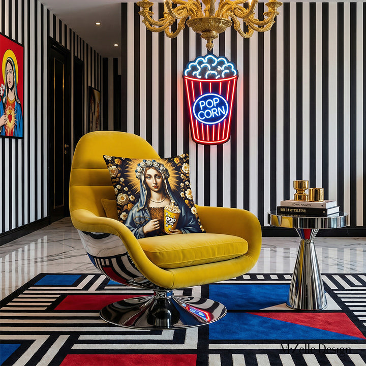 Photographie professionnelle lifestyle,  d'un salon lumineux, vue de face d'un fauteuil noir au design futuriste orné d'un large coussin motif vierge marie , autres éléments de décoration comme un tapis, un chandelier, des livres, au mur un pot de pop corn en néon, ex voto et tapis graphique pop art.