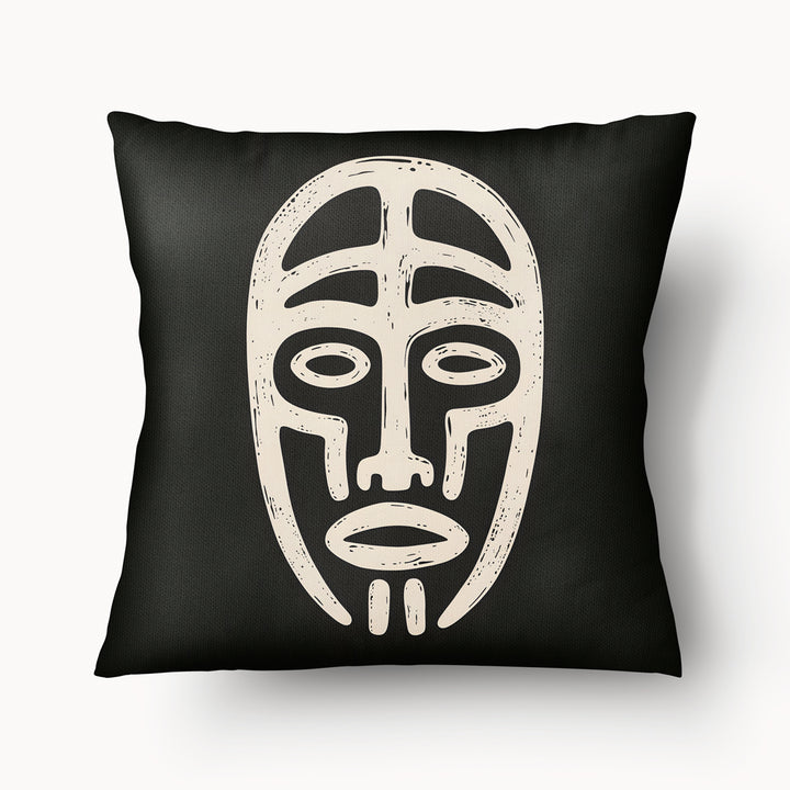 Coussin graphique de décoration de la marque MZelle Design, sur fond noir un motif beige représente un masque tribal, style rupestre moderne