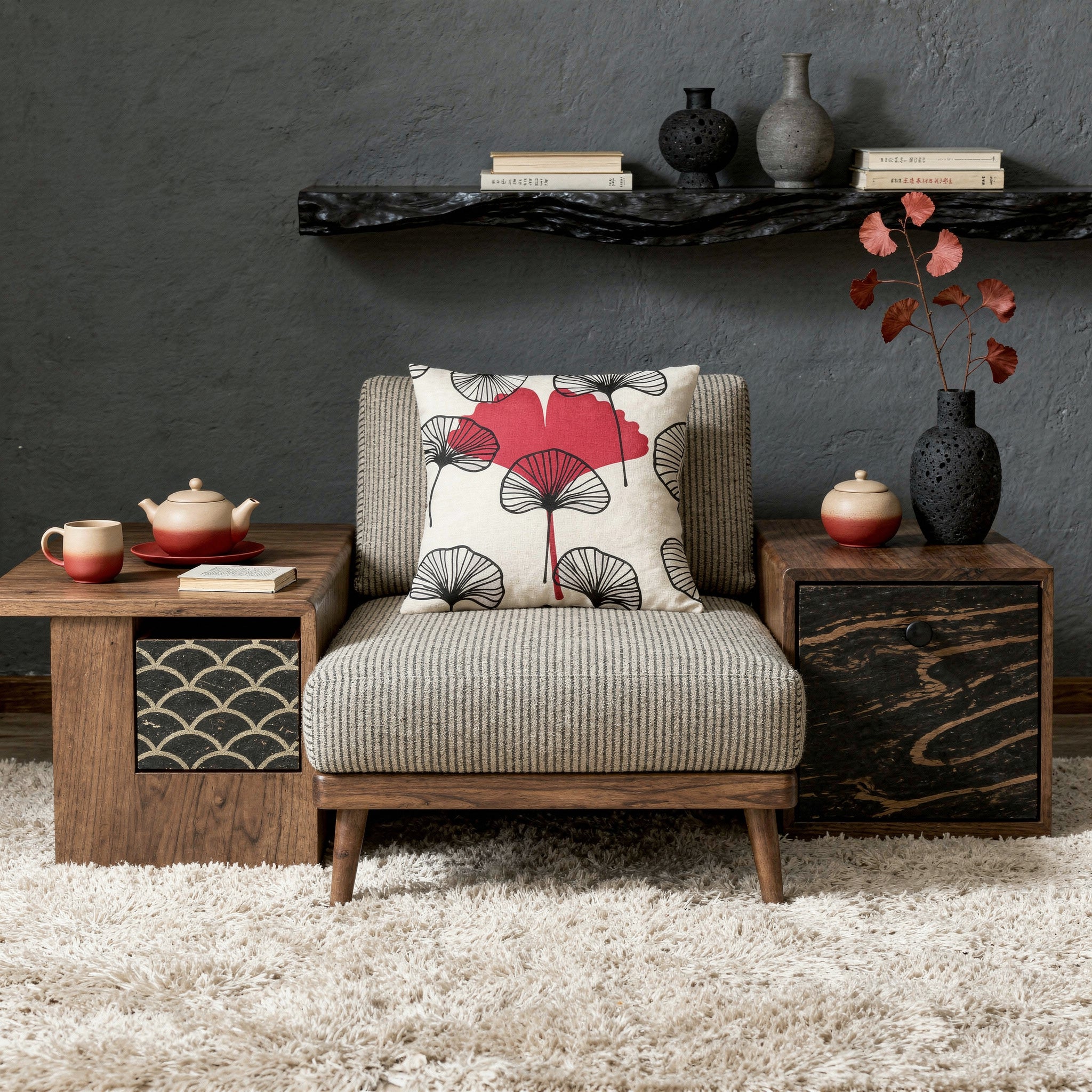 Photographie d'intérieur décoration style japandi-nordique, épuré mais chaleureux, fauteuil-futon moderne assise en lin finement rayé noir et beige orné d'un large coussin mzelle design motif ginkgo graphique, table en bois sur un côté du fauteuil avec un tiroir peint d'un motif en écaille de poisson noir et beige. Service à thé en céramique et vase en pierre noire.