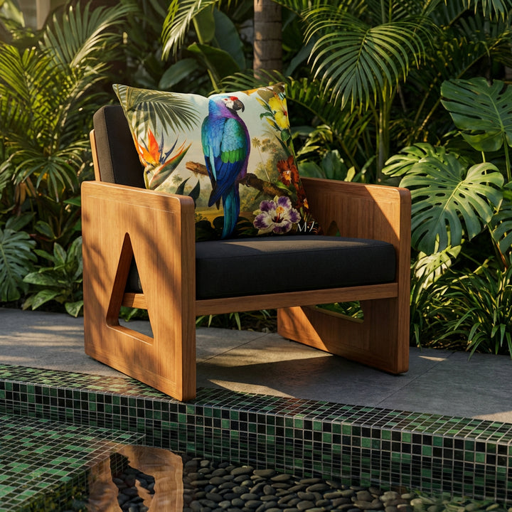 Photographie professionnelle d'un fauteuil en bois teck , sans accoudoirs, assise en twill noir, découpe triangulaire sur les côtés, orné d'un large coussin motif  perroquet mzelle design, disposé dans décor de jardin tropicale avec un bassin d'eau douce en mosaiques noir et vert.