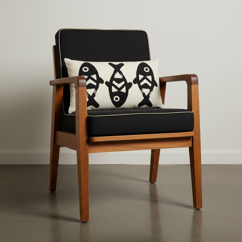 Photographie professionnelle qualité studio, d'un coussin rectangle mzelle design motif poissons, disposé sur une chaise japonaise sans accoudoirs, dossier en tissu noir surpiqué de fil écru, structure épaisse en bois de manguier, disposé dans décor écru neutre.