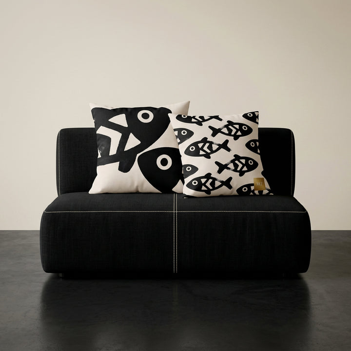 Photographie professionnelle qualité studio, d'un coussin carré mzelle dsign motifs poissons disposé sur une chaise japonaise sans accoudoirs, dossier en tissu noir surpiqué de fil écru, structure épaisse, disposé dans décor écru neutre, sol en béton ciré noir.