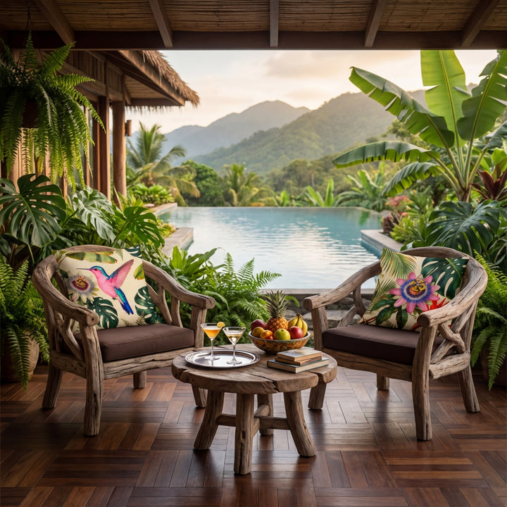 Photographie professionnelle esprit nature, vue de face en gros plan sur 2 fauteuils en bois flotté,  assises marron foncé, ornés de 2 larges coussins motif colibri tropical mzelle design, à gauche et à droite, exposé sur la véranda avec un jardin botanique vue sur piscine.