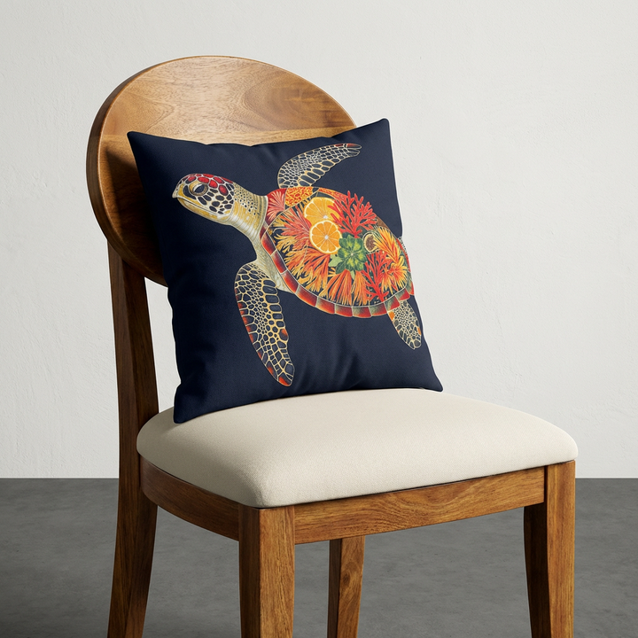 Photographie d'un grand coussin motif tortue marine, disposé sur une chaise créole en bois de manguier verni, sans accoudoirs, dossier en bois arrondi demi lune, assise écru, disposé dans décor écru neutre.