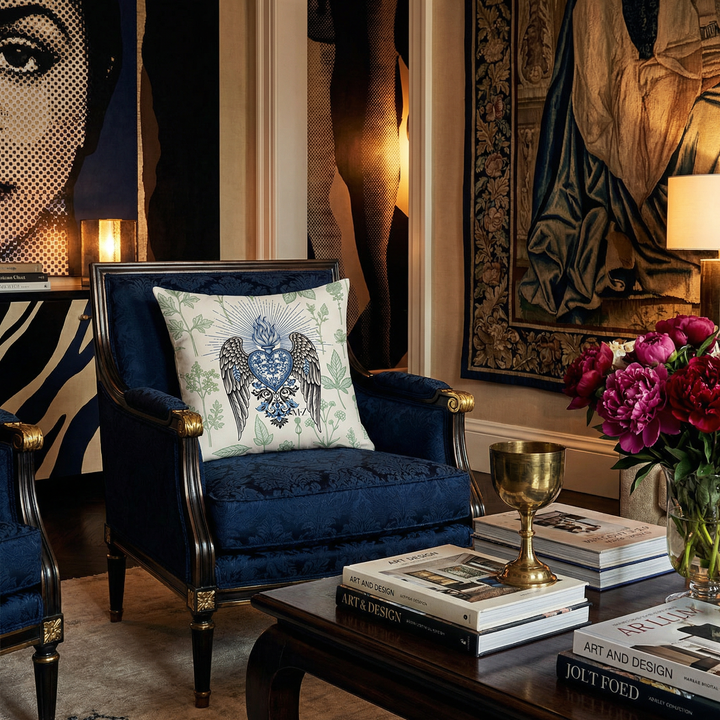 Photographie professionnelle de décoration d'intérieur,  Gros plan de 3/4 sur une chaise Empire assise bleu nuit et rivets cuivrés, ornée d'un large coussin carré avec motif ex voto sur fond ecru, décoration riche. 