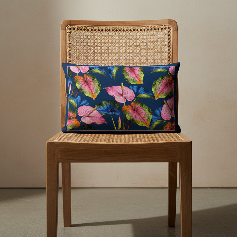 Photographie professionnelle d'un coussin rectangle mzelle design disposé sur une chaise style créole en bois de manguier, dossier en cannage clair, sans accoudoirs, assise en bois,   disposé dans un décor neutre beige.