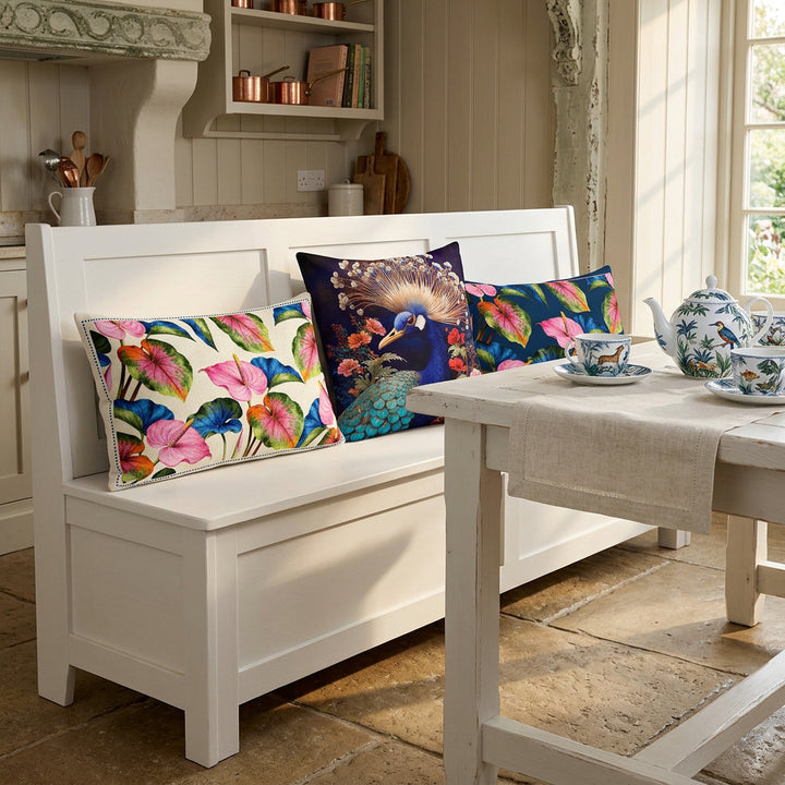 Photo professionnelle de décoration de  cuisine avec un angle aménagé style cottage anglais, avec une banquette-coffre moderne en bois blanc avec une   accumulation maximaliste de 3 coussins décoratifs mzelle design, sol en pierres , table assortie, garnie d'un service à thé en porcelaine fine. Atmosphère printanière raffinée.