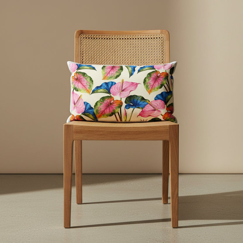 Photographie professionnelle qualité studio, extrêmement détaillée d'un coussin rectangle mzelle design motifs anthuriums tropical, disposé sur une chaise style créole en bois de manguier, dossier en cannage clair, sans accoudoirs, assise en bois,   disposé dans un décor neutre beige.