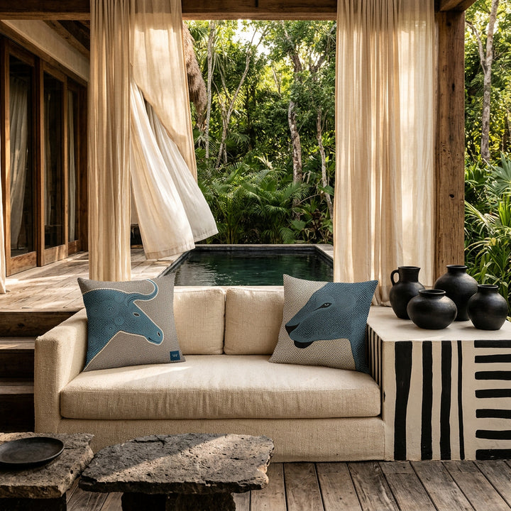 Photo professionnelle lifestyle, décoration terrasse d’eco-lodge tropical haut de gamme, canapé en tissu naturel écru texturé orné de 2 larges coussin mzelle design motif graphique , table basse en pierre volcanique, sol en bois brut, poteries artisanales sur un muret peint de rayures noires, rideaux en lin flottant dans une brise chaude, architecture ouverte sur une jungle luxuriante et piscine sombre moderne.