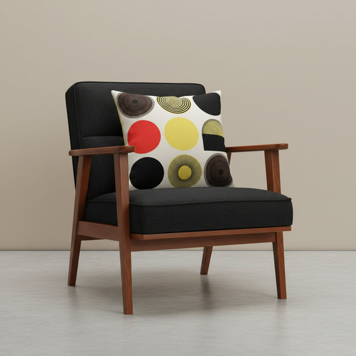 Photographie professionnelle d'un coussin mzelle design vintage bauhaus,  posé sur un fauteuil moderne en bois d'acacia vernis , assise en twill noir finement texturé, disposé dans un décor beige neutre, sobre, sol en ciment couleur unie.