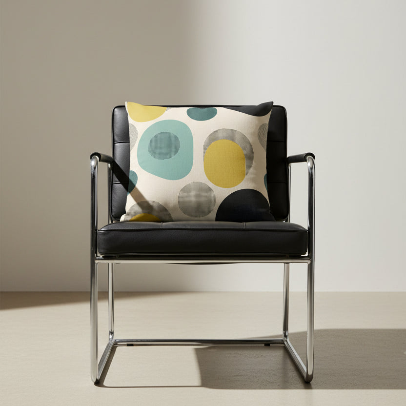 Photographie professionnelle qualité studio, extrêmement détaillée et de haute qualité d'un coussin graphique mzelle design, disposé sur un fauteuil noir et chome d'inspiration BAHAUS, design audacieux à géométrie arrondie, disposé dans décor beige clair.