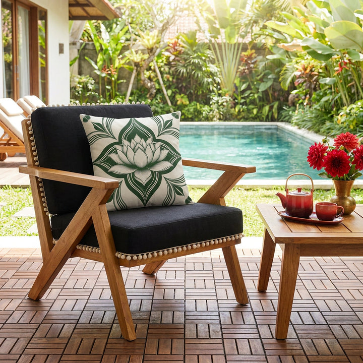 Photo professionnelle de décoration d'une maison à Bali, scène baignée de soleil , gros plan de face sur un fauteuil moderne en bois de manguier  assises lin noires finitions petits pompons écrus, orné d'un large coussin mzelle design, motif lotus, dalles de caillebotis en bois au sol, table basse assortie avec un service à thé. Piscine et jardin.