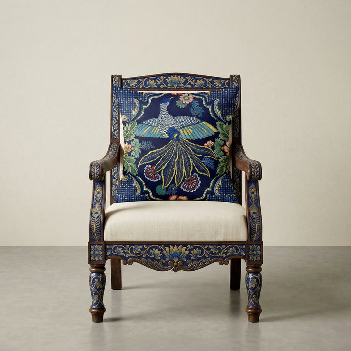 Photographie professionnelle de décoration, montrant un superbe fauteuil Indien Style dravidien, assise en coton écru, structure en bois de manguier peint à la main de motifs floraux Indien bleu vif et doré, orné d'un large coussin motif oiseau mzelle design et disposé dans décor écru neutre.