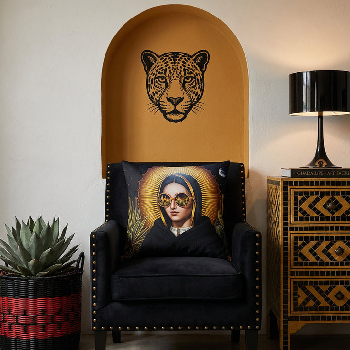 Photographie professionnel décoration  loft mexicain, chaise en velours noir finitions rivets laiton design moderne, orné d'un large coussin mzelle design motif vierge marie, placé devant une niche en arche ocre dans le mur en pierres blanchies, décoré d'un EX VOTO en laiton et d'une tête de jaguar en peinture noir. 