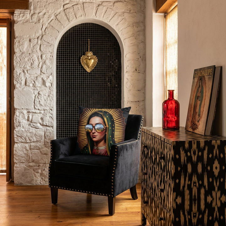 Photographie professionnel décoration intérieure de loft mexicain, vue de face d'une chaise en velours noir finitions rivets laiton design moderne, orné d'un large coussin mzelle design motif vierge marie, placé devant une niche en arche de mosaiques noir dans le mur en pierres blanchies, décoré d'un EX VOTO en laiton, commode peinte.