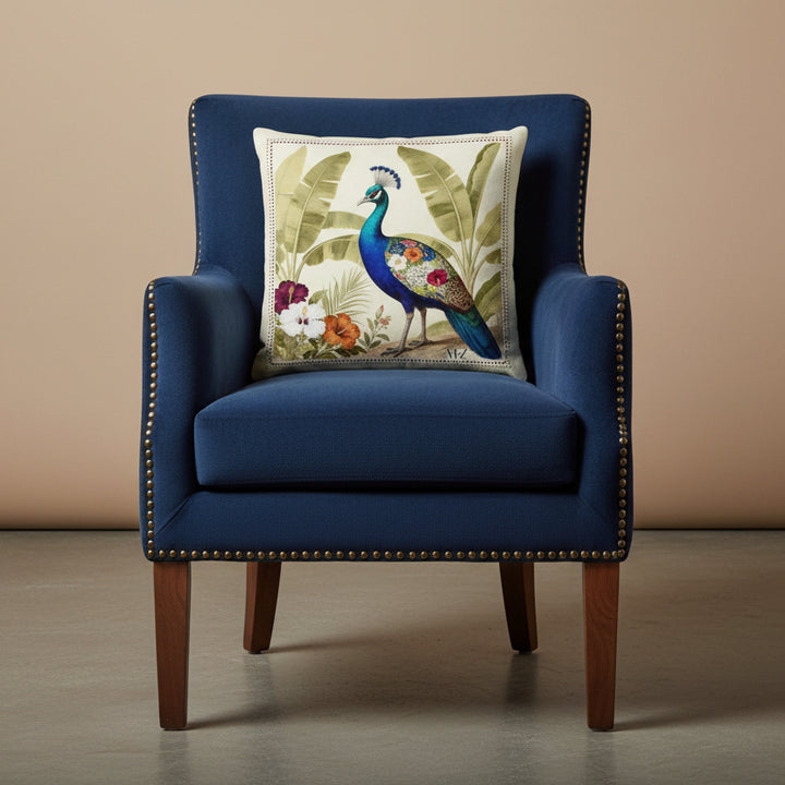 Photographie professionnelle qualité studio, extrêmement détaillée et de haute qualité d'un coussin mzelle design motif paon bleu, disposé sur un fauteuil crapaud en velours mat bleu nuit, rivet en laiton, bois de noyer, sans accoudoirs, disposée dans un décor minimaliste, neutre beige.