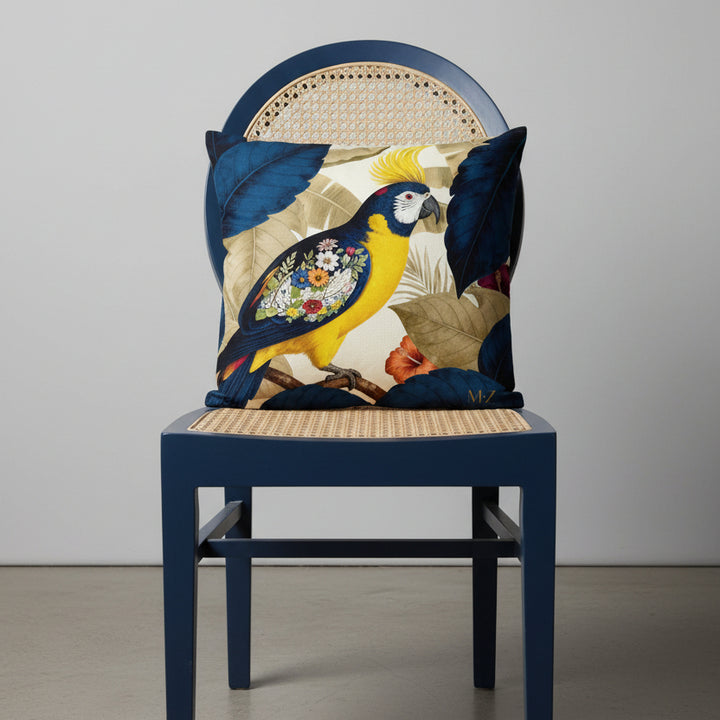 Photographie professionnelle qualité studio, extrêmement détaillée et de haute qualité d'un coussin mzelle design motif perroquet, disposé sur une chaise de style créole en bois peint bleu marine, cannage beige, dossier demi lune, sans accoudoirs, disposée dans un décor neutre gris clair.