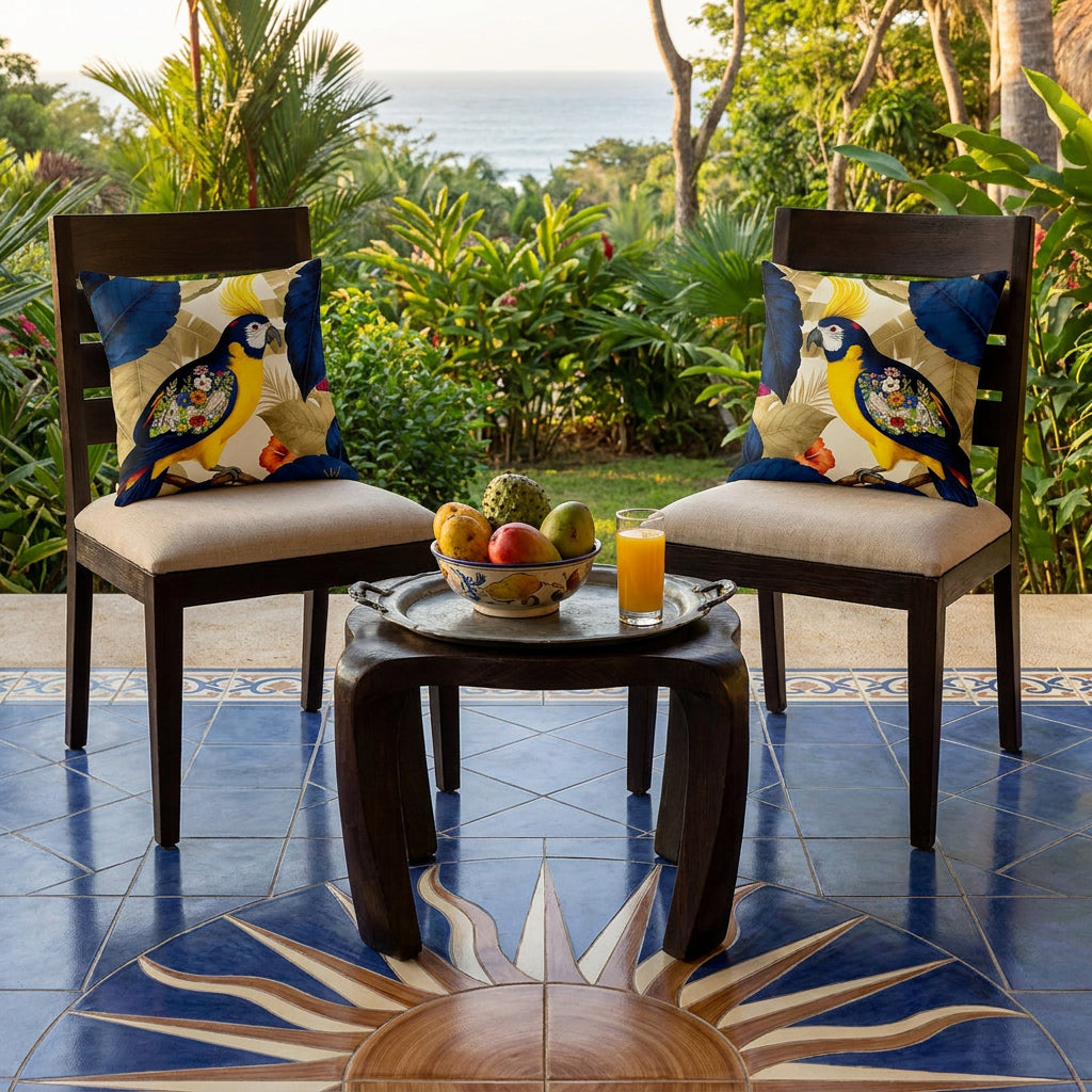 Photo professionnelle lifestyle,  décoration villa au costa-risca, vue de face d'un 2 chaises en bois de wengé verni et assises écrues en lin, sans accoudoirs, ornée chacune d'un coussin décoratifs mzelle design motif perroquet bleu et jaune, sol en carrelage formant un soleil, table en wengé sculptée, garnie d'un plateau en étain avec une coupe de fruits tropicaux (mangues et attiers) et un verre de jus de fruit, Atmosphère estivale. 