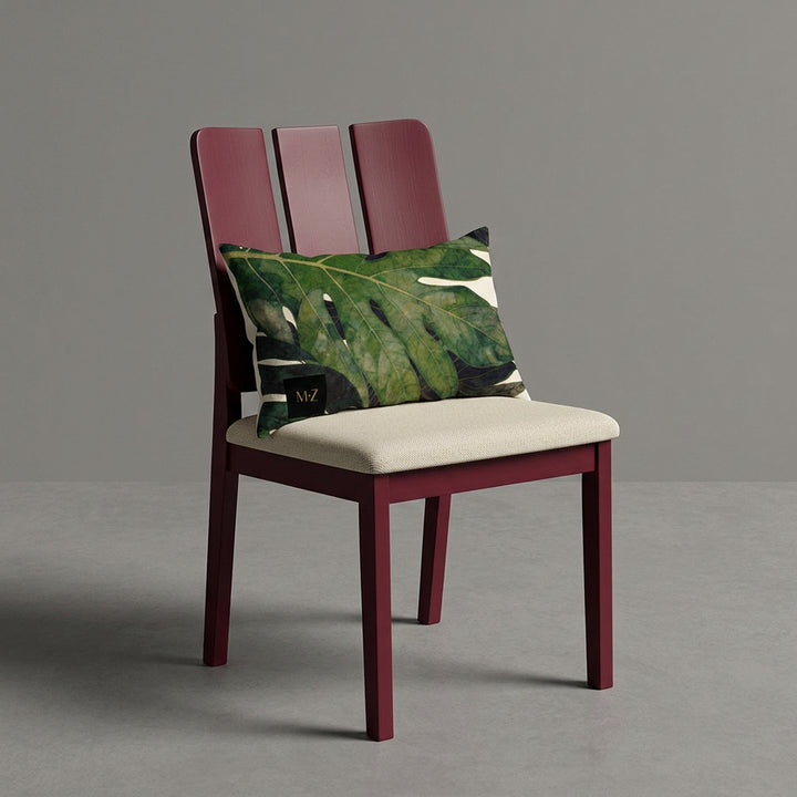 Photographie d'un grand coussin rectangle mzelle design motif fruit tropical disposé sur un fauteuil de style créole, en bois précieux disposé sur un fond neutre, qualité studio photo. 