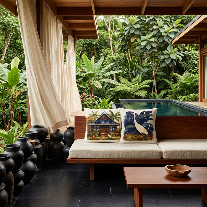 Photo professionnelle lifestyle, décoration terrasse d’eco-lodge du costa-rica, banquette moderne bois de mahogany orné de deux coussins mzelle design motif maison créole et oiseau, table basse assortie, sol en carrelage noir, poteries artisanales empilées de façon artistique dans un muret , rideaux en lin crème flottant , architecture ouverte sur une jungle luxuriante et piscine sombre moderne.