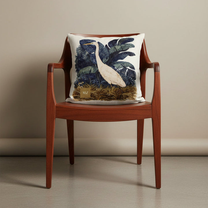 Photographie professionnelle extrêmement détaillée et de haute qualité d'un coussin mzelle design motif héron créole, disposé sur un fauteuil japonais moderne en bois de mahogany laqué, assise en bois, disposé contre un mur, dans un décor beige neutre.