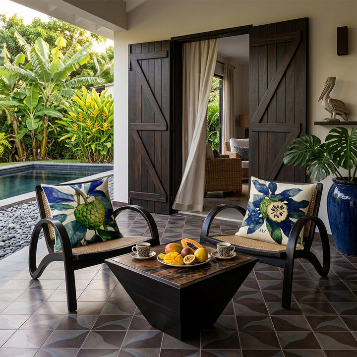 Photo décoration villa caribéenne, sublimes chaises en ébène au design moderne, ornées de coussin carré mzelle design motif tropical, table basse avec plateau assorti et 2 tasses de café et assiette de fruits, en arrière plan aperçu d'un salon par fins rideaux en lin, au sol un carrelage géométrique. vue sur jardin tropical et  piscine. Ambiance d'art de vivre Créole.
