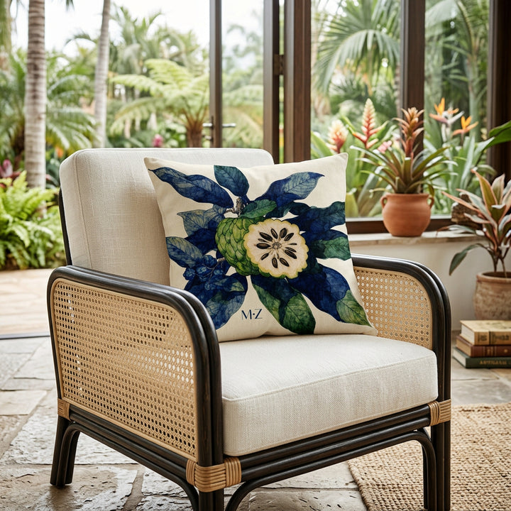 Photographie professionnelle d'aménagement intérieur, mettant en scène un superbe fauteuil de style contemporain en rotin teinté foncé, orné d'un grand coussin carré mzelle design motif fruit tropical,  l'assise et le dossier sont en tissu texturé lin beige, avec cannage écru sur les côtés, exposé dans un lodge tropical lumineux, vue jardin.