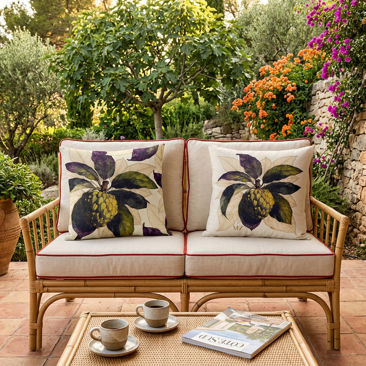 Photo professionnelle de décoration  d'une villa provençale baignée de soleil ,gros plan de face sur une banquette 2 places au design moderne en bambou tressée , ornée de chaque côté d'un large coussin mzelle design motif fruits tropicaux attier, carrelage tomette au sol, table basse en bambou tressé avec 2 tasses de café et un magazine.