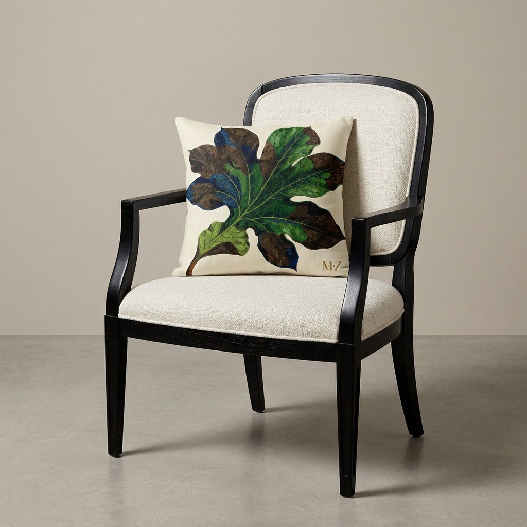 Photographie professionnelle vue de 3/4, extrêmement détaillée et de haute qualité d'un grand coussin  mzelle design motif feuille, disposé sur une chaise moderne de forme arrondie, disposé dans décor beige neutre.