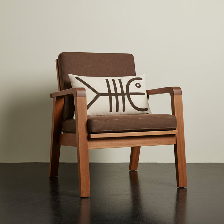 Photographie professionnelle qualité studio, d'un coussin rectangle mzelle design motif tribal, disposé sur une chaise japonaise sans accoudoirs, dossier en tissu brun cacao surpiqué de fil écru, structure épaisse en bois d'acacia.