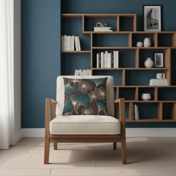 Décoration d'interieur avec un fauteuil orné d'un Coussin décoratif style moderne Mzelle design, aux motifs all over feuille de ginkgo délicatement stylisés, fleurs écru sur fond marron foncé.