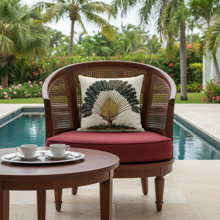 Photographie professionnelle vue de face d'un superbe fauteuil arrondi en bois verni, dossier en cannelage, assise en lin rouge foncé, orné du coussin carré imprimé au centre, arrière plan jardin luxuriant et piscine