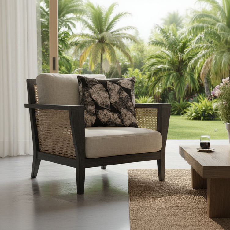 Photographie professionnelle d'aménagement intérieur, mettant en scène un superbe fauteuil de style contemporain en rotin teinté foncé, orné d'un grand coussin carré mzelle design motif tropical,  exposé dans un lodge tropical lumineux, vue jardin.