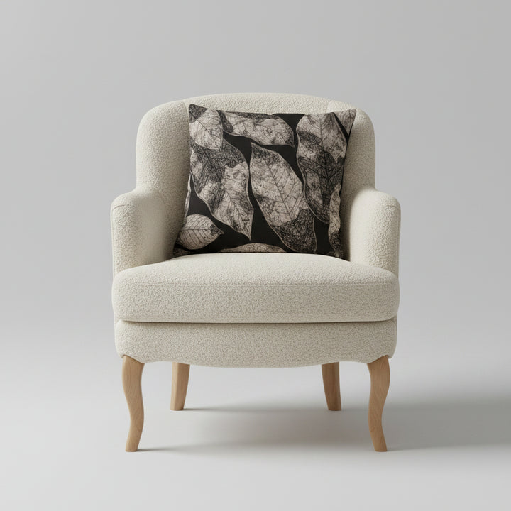 Photographie qualité studio,  d'un grand coussin carré mzelle design disposé sur un fauteuil crapaud en bois clair et assise de laine bouclée écrue, disposé sur un fond neutre.