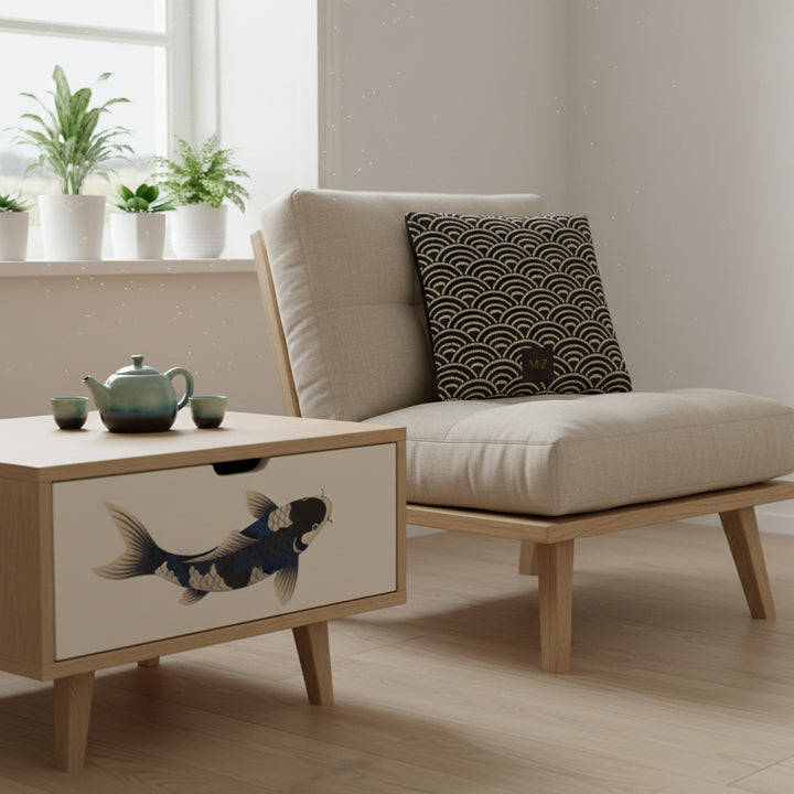 Photographie d'intérieur décoration  japandi, épuré mais chaleureux, fauteuil-futon moderne assise en lin beige orné d'un grand coussin mzelle design, table en bois clair avec un tiroir peint d'un motif poisson Koi noir, bleu et beige. Service à thé en céramique dégradé vert et bleu.

