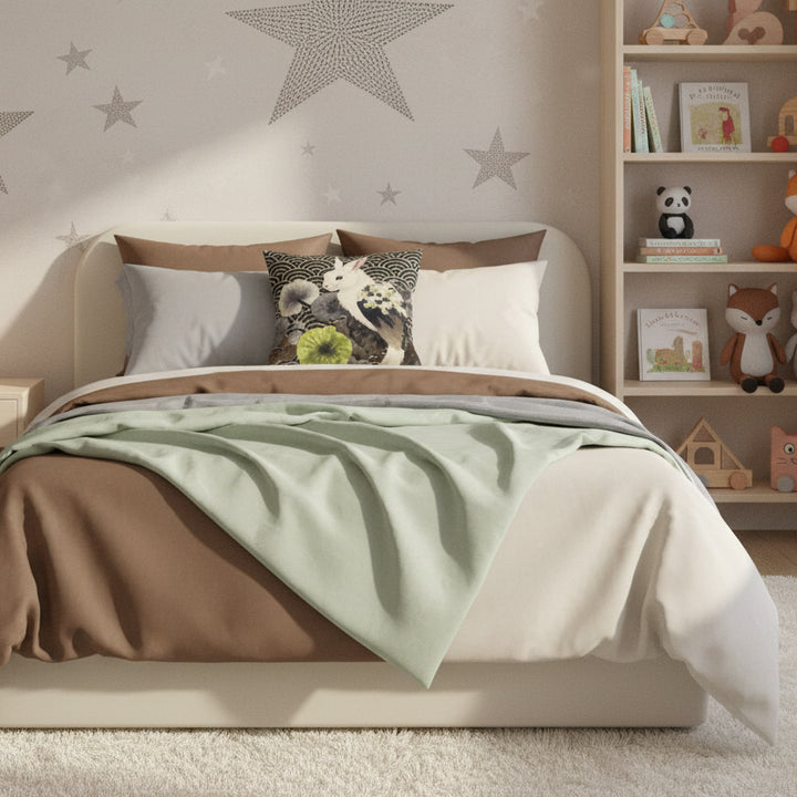 Photographie d’intérieur décoration de chambre d’enfant , vue de face d'un lit orné du coussin mzelle design au centre posé contre 2 oreillers, mur principal orné d’une fresque d’étoiles stylisées peintes à la main, détails pointilleux et délicats, tapis moelleux texturé, petits meubles design enfant. 